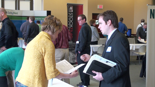 People having a discussion in a room with an information booth and tables