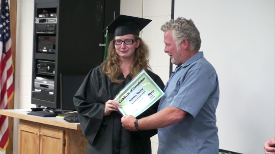 Older gentlemen handing a young women a certificate